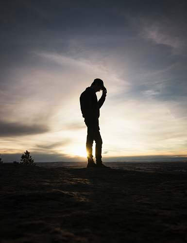 person silhouette man standing holding cap during sunset people