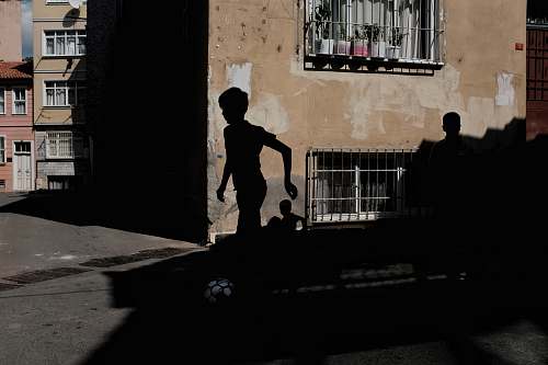 person silhouette of boy running near brown concrete building during daytime people