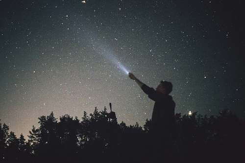 person silhouette of man looking up during nighttime grey