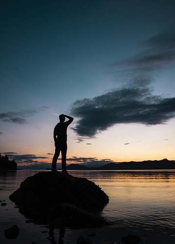 person silhouette of man standing on rock silhouette