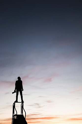 person silhouette of man standing on slide while holding camera grey