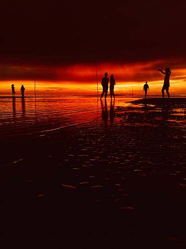 person silhouette of people beside of body of water outdoors