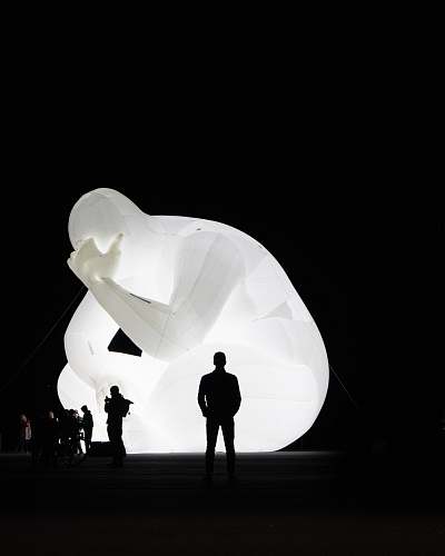 person silhouette of people standing beside lighted statue silhouette