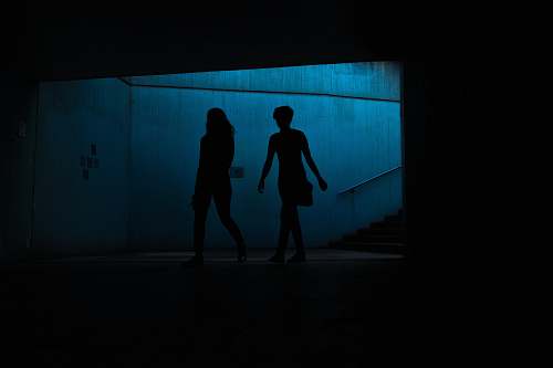 person silhouette of two persons underpass people