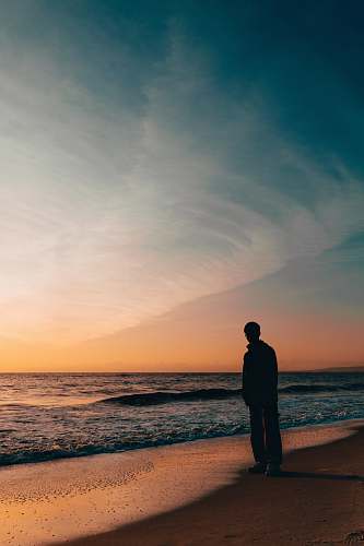 nature silhouette person standing beside seashore during sunset beach