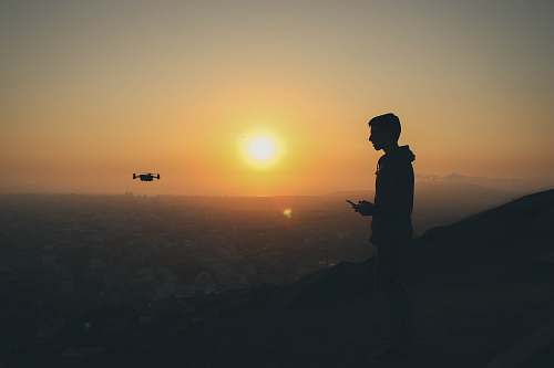 person silhouette photo of man holding drone remote people
