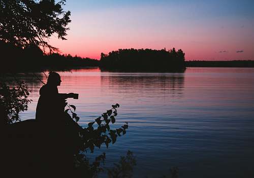 people silhouette photo of man sitting beside body of water person