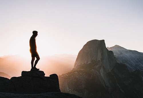 person silhouette photo of man standing on hill standing