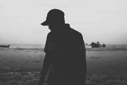 black-and-white silhouette photo of person in cap grey