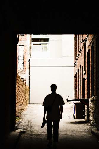 person silhouette photography of man holding camera standing in front of wall people
