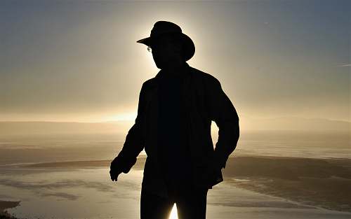 person silhouette photography of man wearing cowboy hat people
