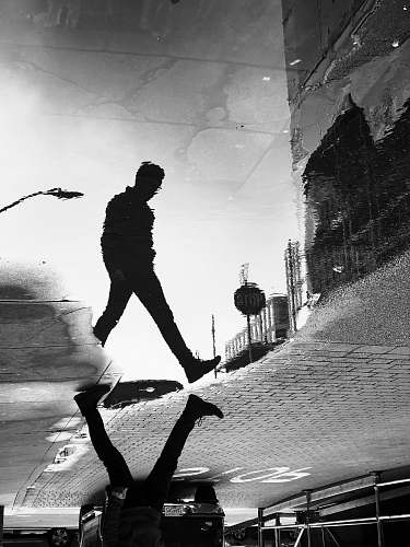 person water reflection shadow of man walking on street in grayscale photography black-and-white