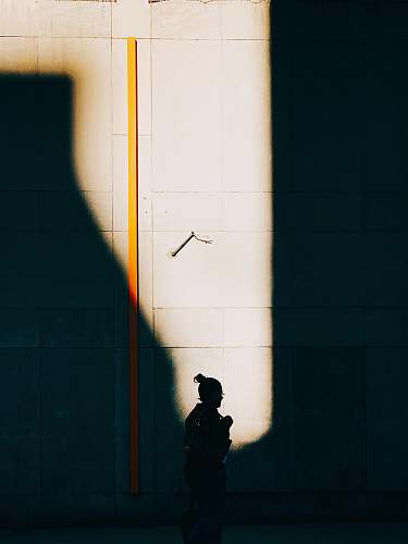 person woman walking beside wall silhouette