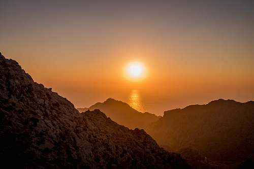 sunrise landscape photo of brown mountains near body of water mountains