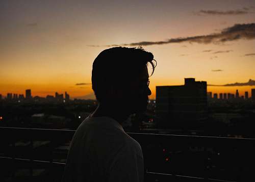 human man standing near railings viewing city person