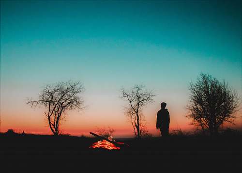 outdoors man standing silhouette near bonfire silhouette