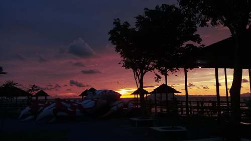 outdoors orange setting sun in horizon over beach with cottages dawn