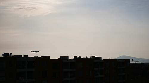 outdoors silhouette of buildings and airplane under white sky silhouette