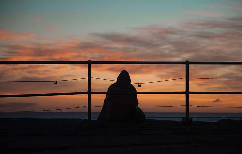 silhouette silhouette of person sitting near railings outdoors