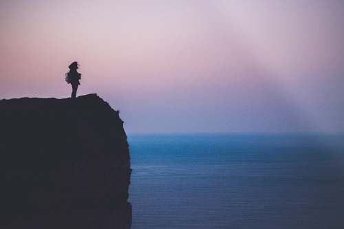 outdoors silhouette of person standing on sea cliff during golden hour cliff
