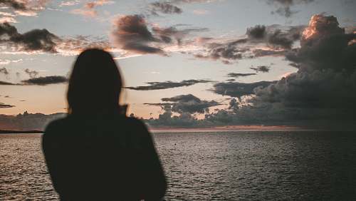 outdoors silhouette of woman standing on beach watching setting sun silhouette