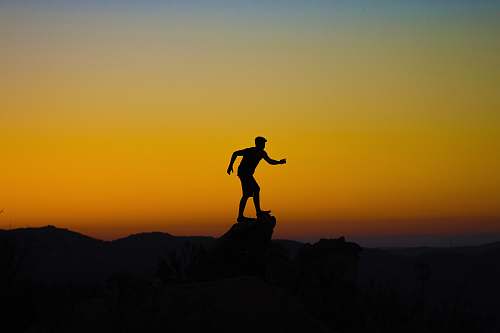 sunset silhouette photo of person on mountain cliff sunrise