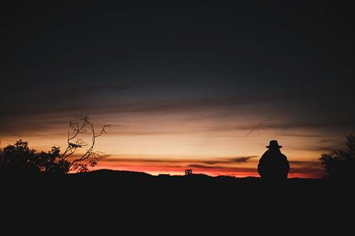 silhouette silhouette photography of person sitting on mountain outdoors