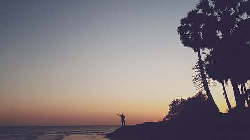 outdoors silhouette photography of person standing on shore silhouette