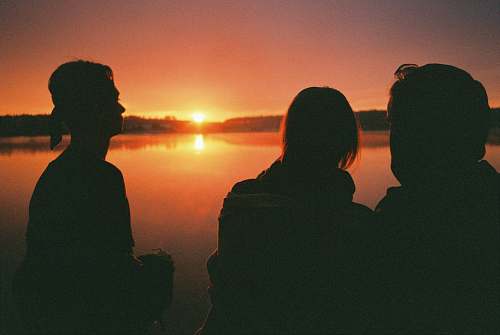 outdoors three people by a lake at sunset human