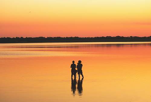 human two people standing on body of water during daytime person