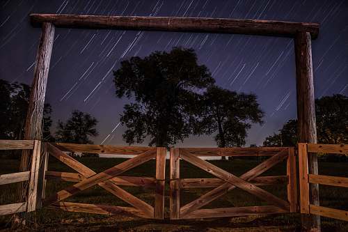 stars worm's eye view photography of brown wooden barn doors fence