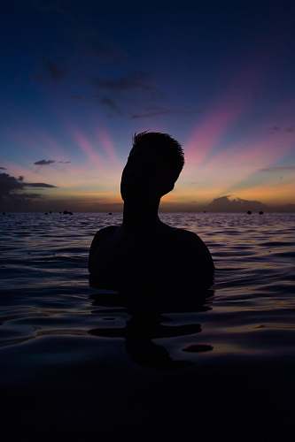 sunset person in body of water during golden hour water