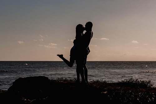 human silhouette of kissing couples near sea person