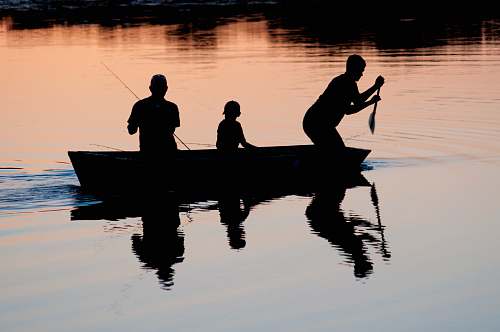 person silhouette of three person riding on boat on body of water human