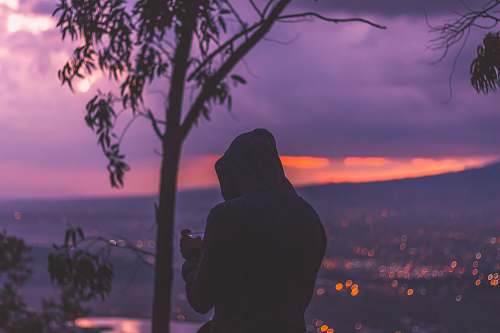 person silhouette photo of man standing at the peak facing cityscape human