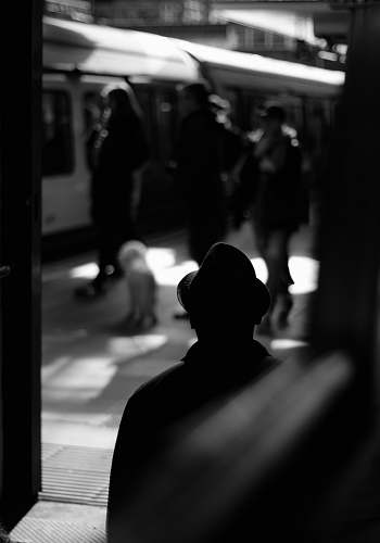 human grayscale photo of person standing on train station black-and-white