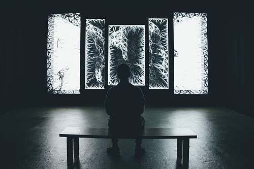 human grayscale photography of man sitting on bench bench