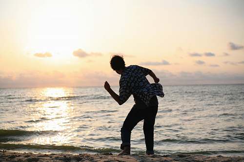 human man about to throw stone on sea sea