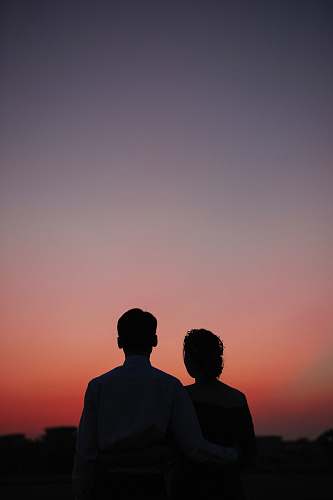 silhouette man and woman standing and looking sunset nature