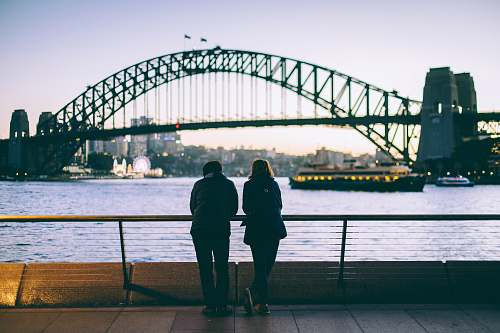 human man and woman standing beside each other in front of body of water people
