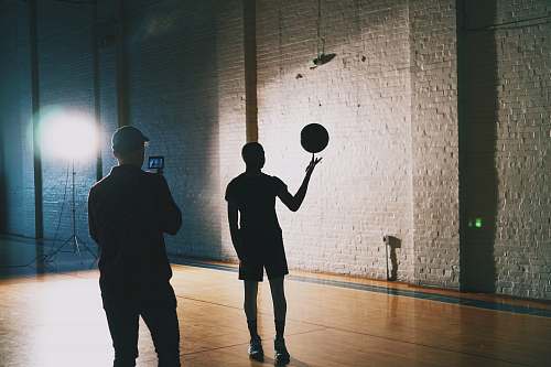 human man capturing silhouette photo of man spinning basketball people
