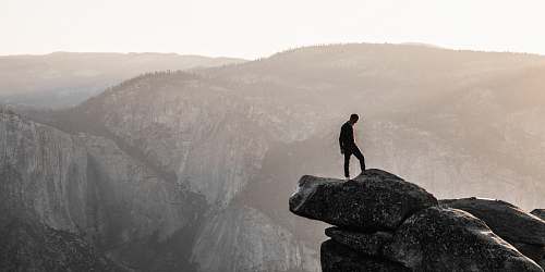 rock man standing on top of mountain during daytime landscape