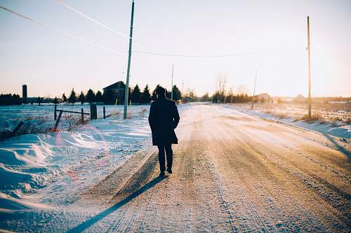 human man walking in the middle of the road covered with snow people