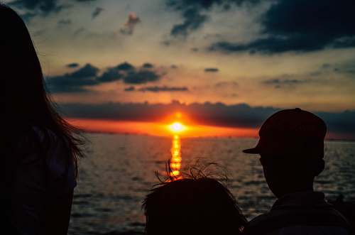 human silhouette of children looking on orange sunset above sea people