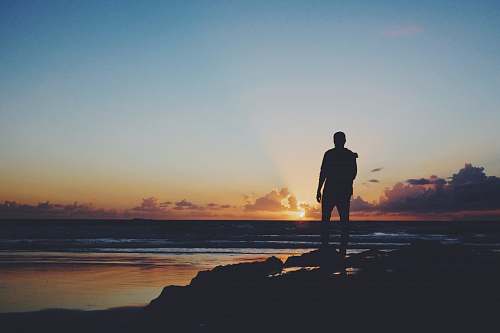 people silhouette of man standing near shoreline human