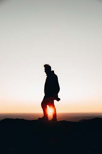 silhouette silhouette of man standing on cliff during golden hour human