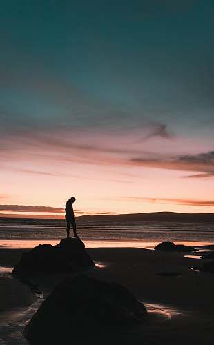 human silhouette of man standing on rock standing