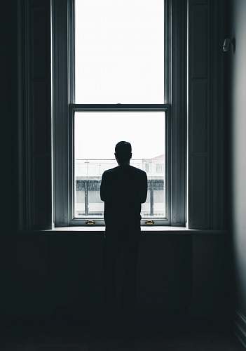 human silhouette of person standing in front of window at daytime people