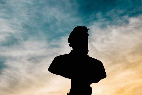 human silhouette of statue bust of man under cloud sky during daytime people
