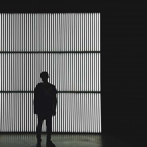 silhouette silhouette photo of a person standing near wall in dark room black-and-white